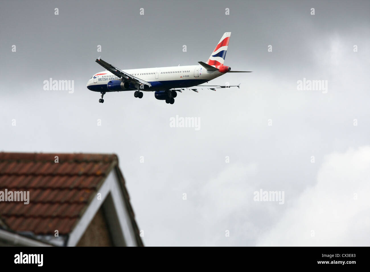 An aircraft flying over houses as it comes in to land at Heathrow airport Stock Photo