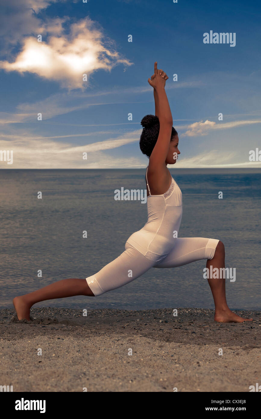a young woman is doing yoga at the beach Stock Photo