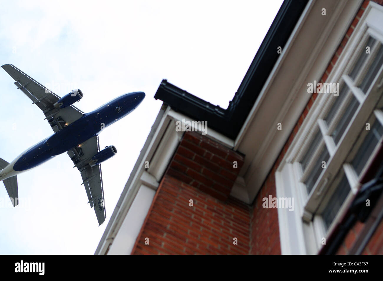 An aircraft flying over houses as it comes in to land at Heathrow airport Stock Photo