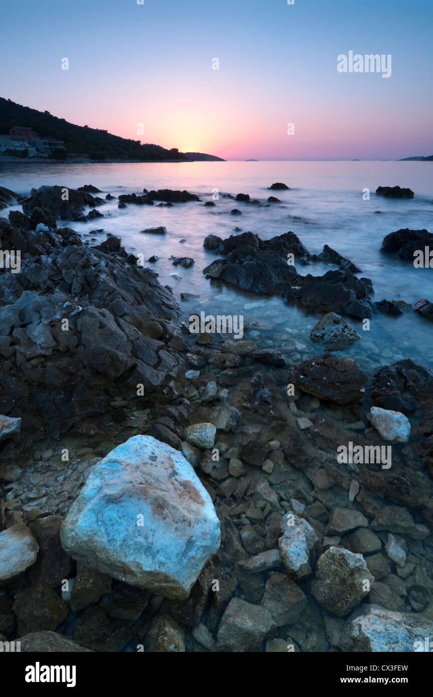 Sea view at sunset with transparent water and rocks and stones in foreground Stock Photo