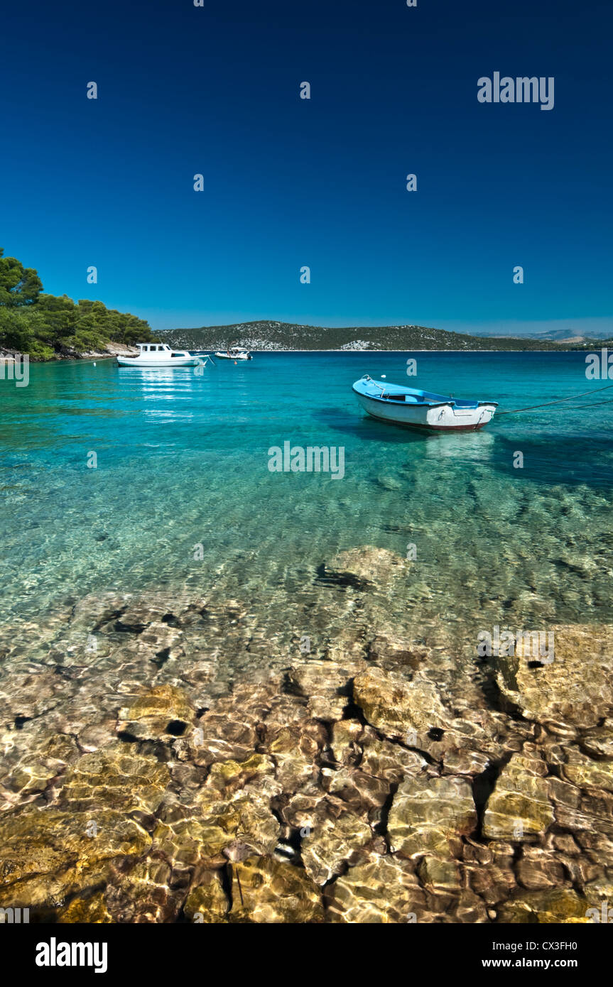 Transparent water with a boat and mountains in background. Bilo, Dalmatia, Croatia Stock Photo