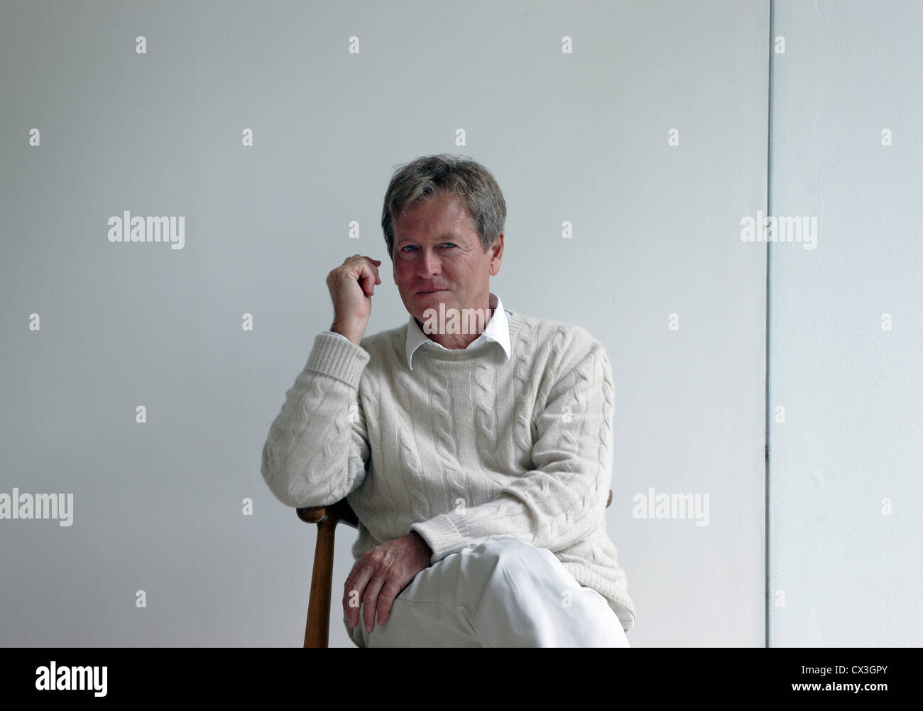 John Pawson at home, London, United Kingdom. Architect: John Pawson, 2010. Portrait of John Pawson sitting on a chair with one a Stock Photo