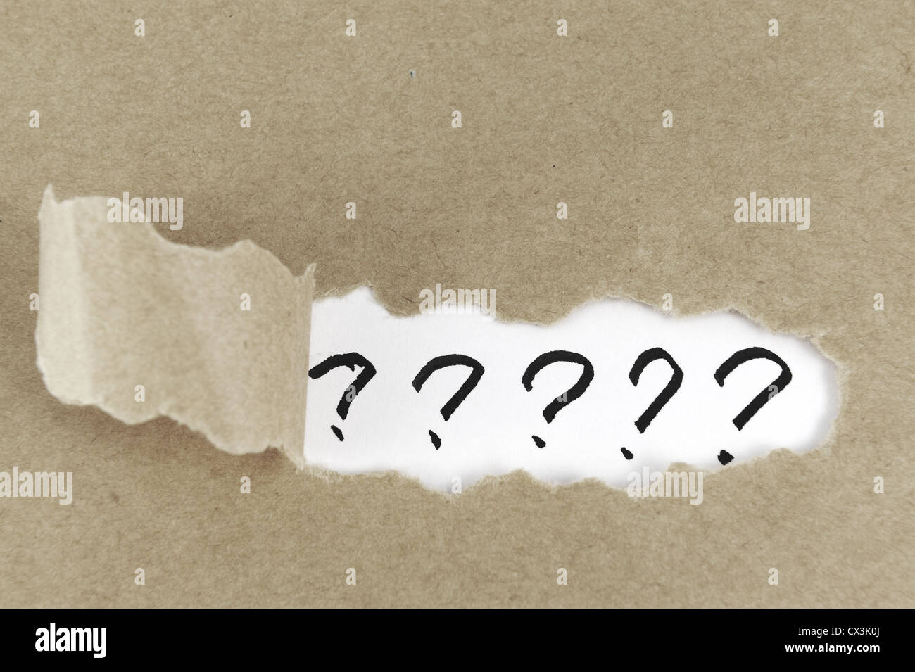 Torn paper with group of question mark behind it Stock Photo