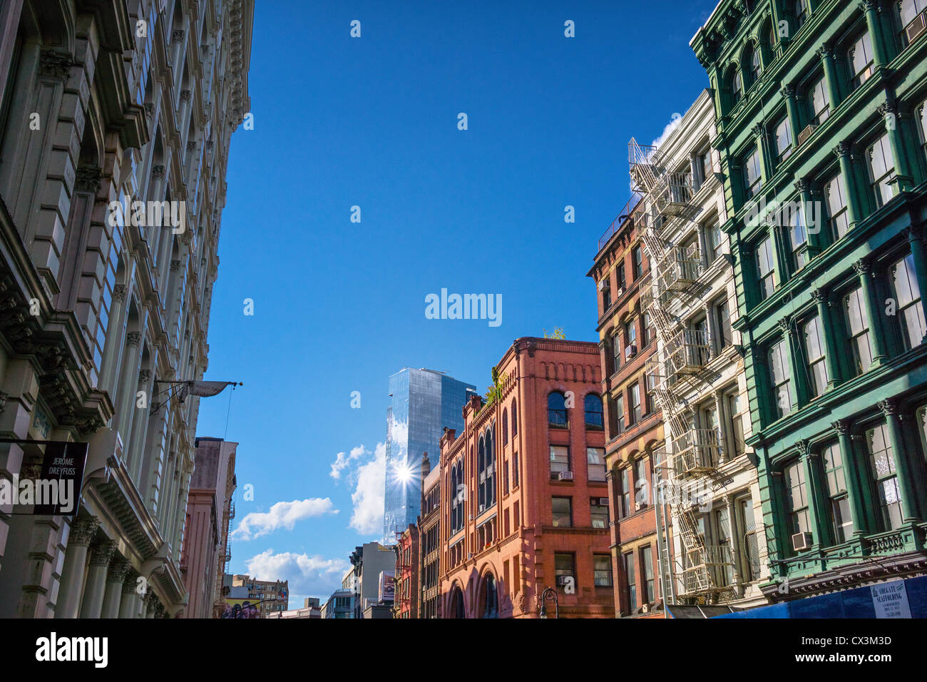 Old loft buildings with fire escapes on Broome Street in SoHo-Cast Iron Historic District with the glass Trump SoHo in the distance Stock Photo
