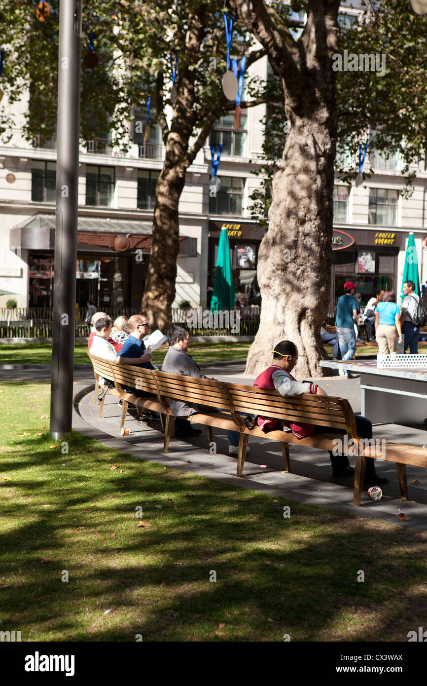 People sitting on the benches in the newly revamped Leicester Square in London Stock Photo