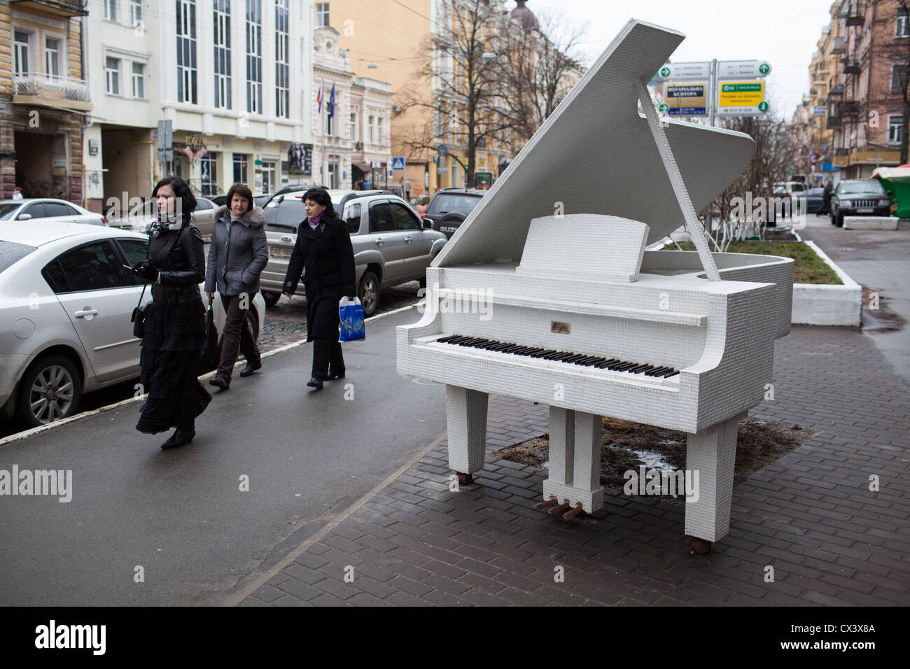 Pedestrians pass a white grand piano monument in downtown Kiev, Ukraine, Eastern Europe Stock Photo