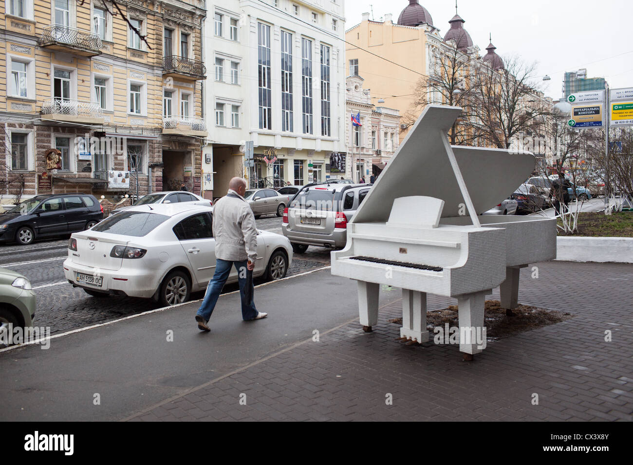 Pedestrians pass a white grand piano monument in downtown Kiev, Ukraine, Eastern Europe Stock Photo