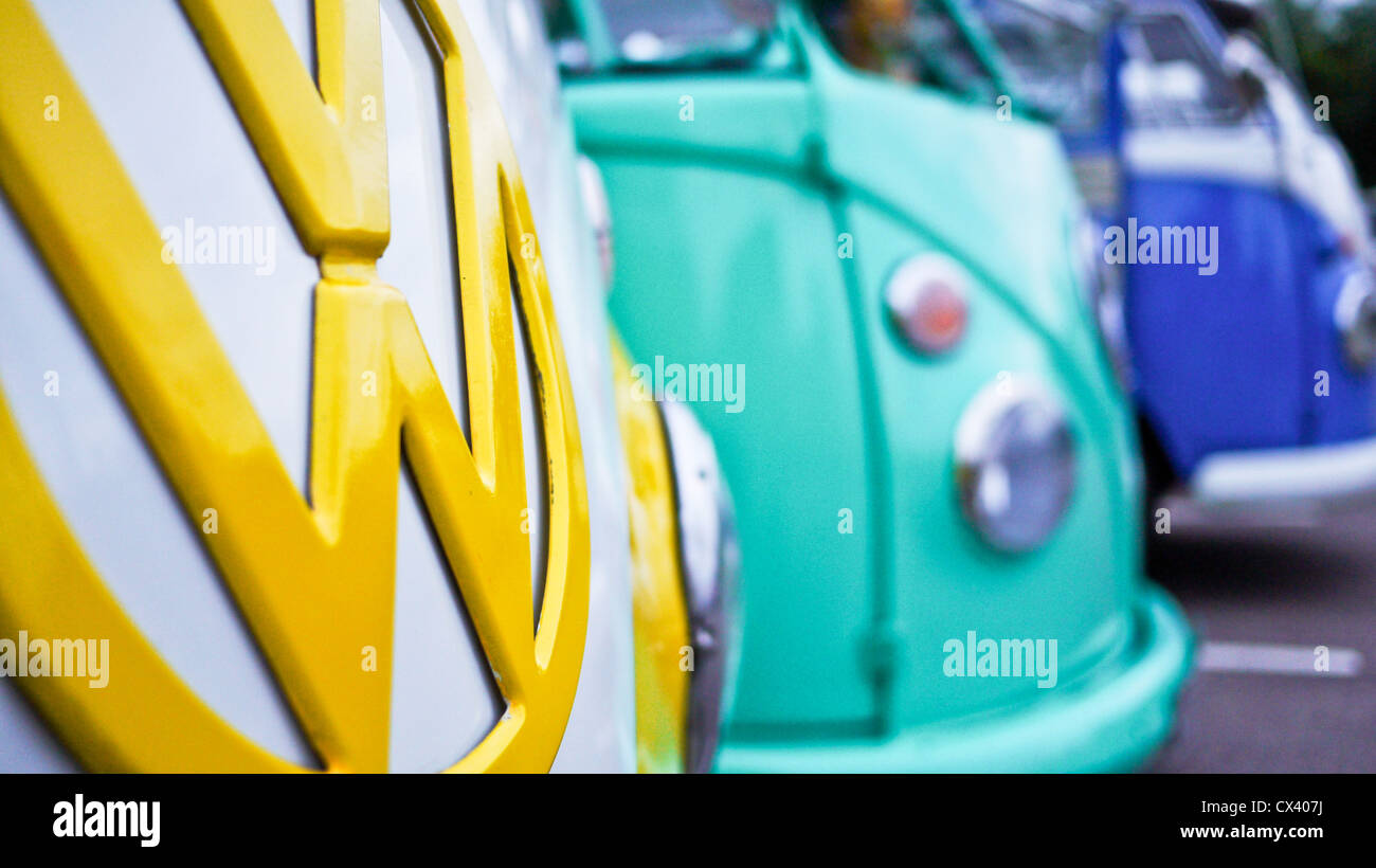 Close up of yellow Volkswagen badge, with other colourful VW Campers in view at the Dunstable Dubbers meet. Stock Photo
