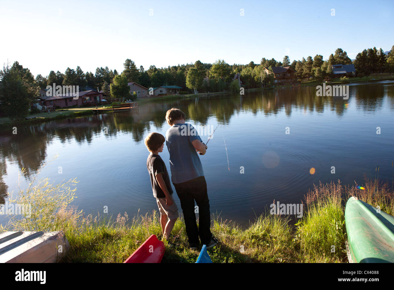Older brother, age eleven, teaching younger brother how to use a fishing rod at a lake in Colorado, USA. Stock Photo
