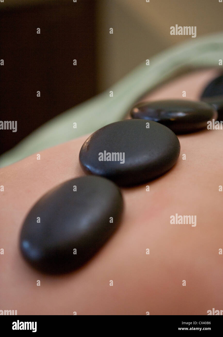 Hot stone treatment using warm, oiled river rocks on client's spine to