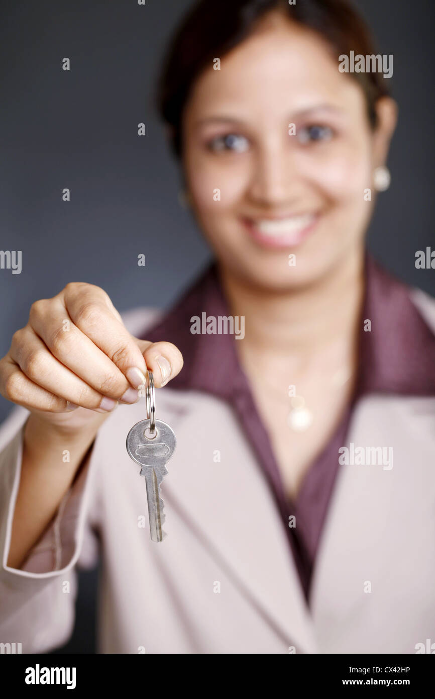 Smiling young business woman showing a key Stock Photo - Alamy