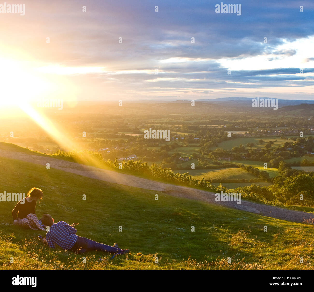 Panorama at dusk from Malvern Hills with two teenagers in suns rays Worcestershire England Europe Stock Photo