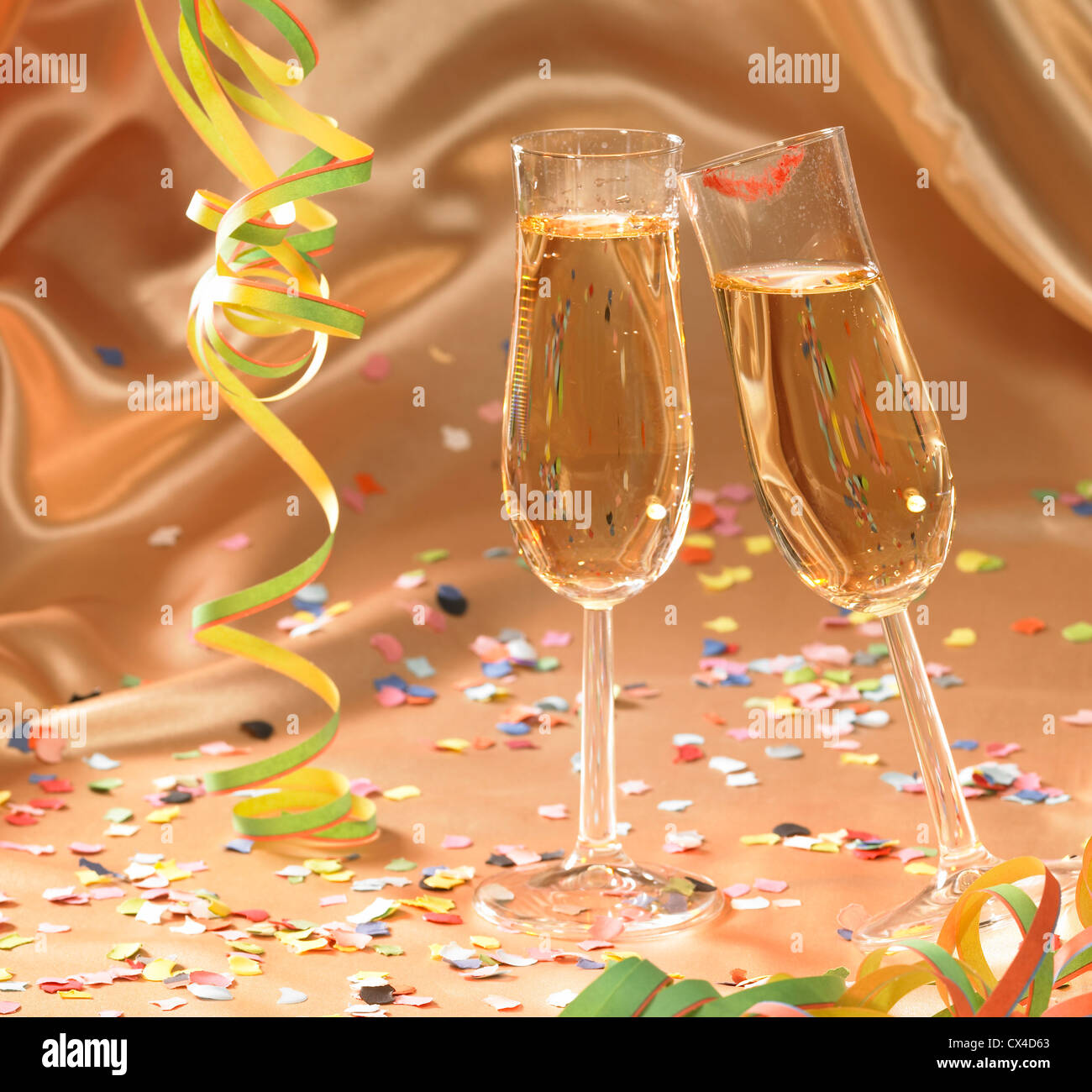 party background with filled champagne glasses in floating satin back with streamers and confetti Stock Photo