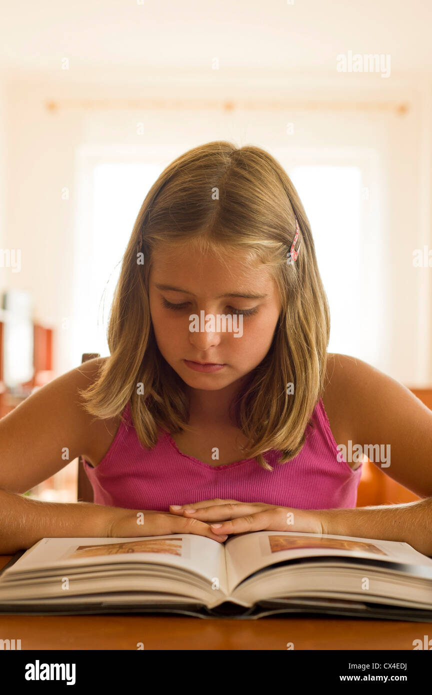 8-9 year girl reading or studying a book at the table Stock Photo