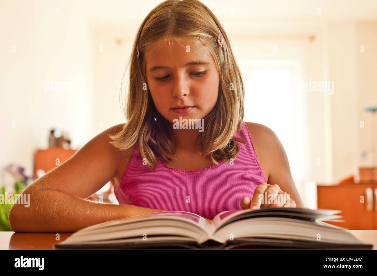 8-9 year girl reading or studying a book at the table Stock Photo