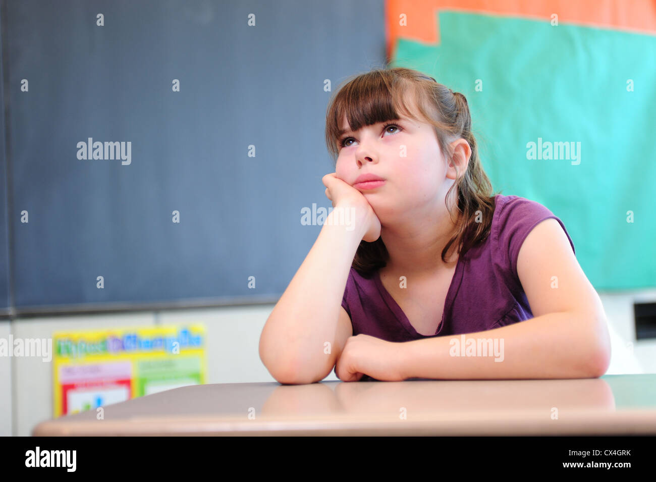 USA A third 3rd grade girl sits bored in a classroom at her public school Stock Photo
