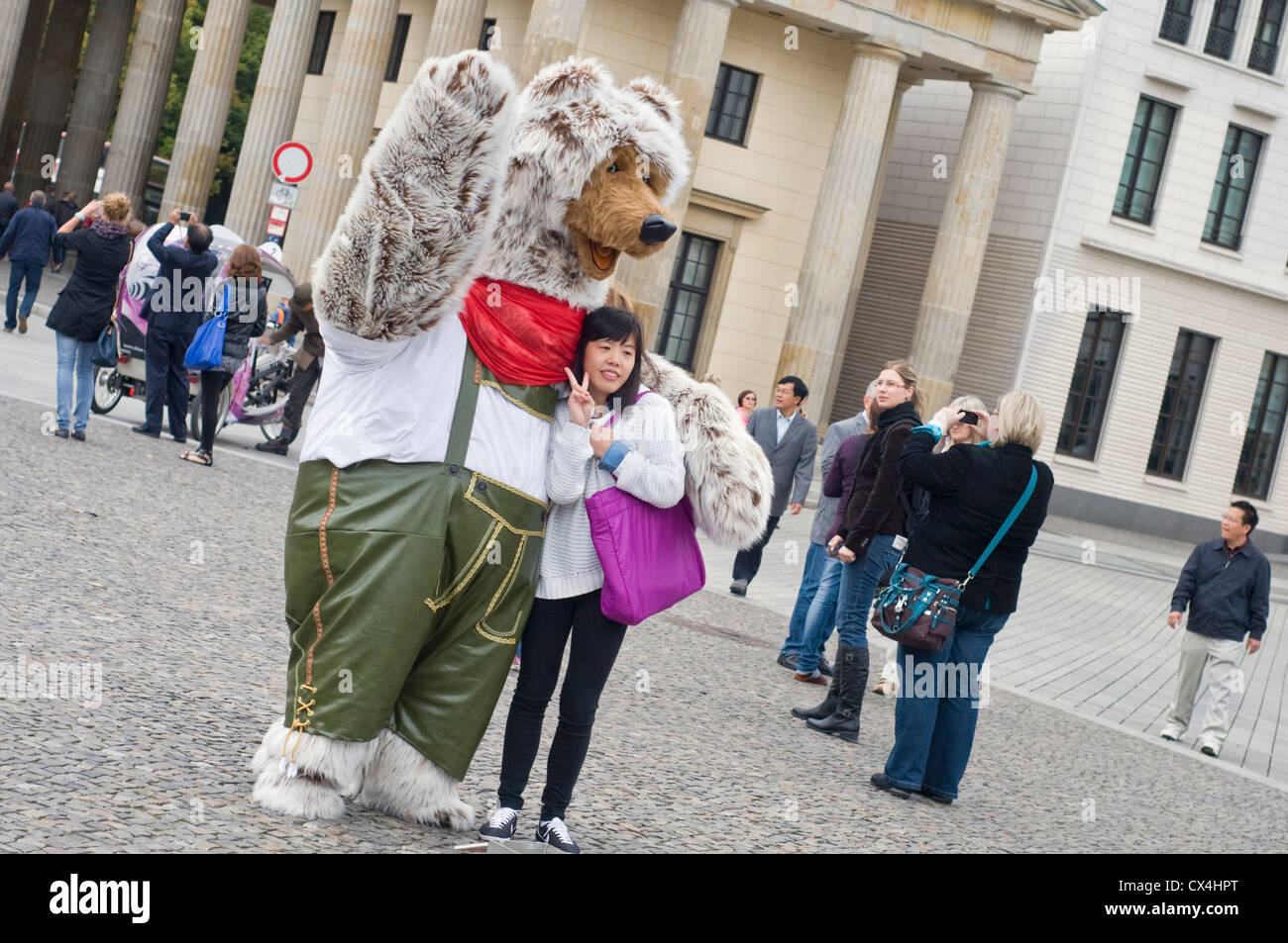 A tourist having her photo taken with someone dressed as bear in front of the Brandenburg Gate in Berlin, Germany Stock Photo