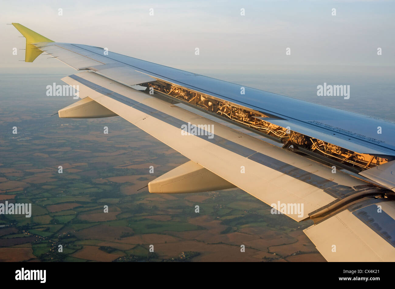 Wing of an Airbus A319 commercial airliner with flaps down coming into land at London Stansted airport, Essex, UK. Stock Photo