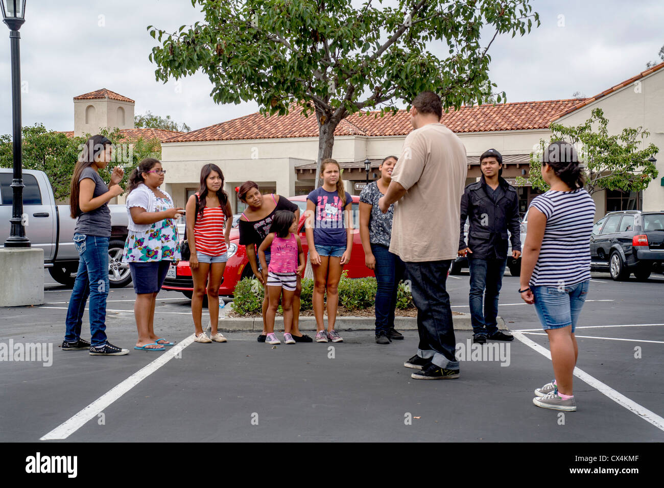 A interracial group of children yells 'stop' to a bully intimidating a child (foreground) in a California parking lot. Stock Photo