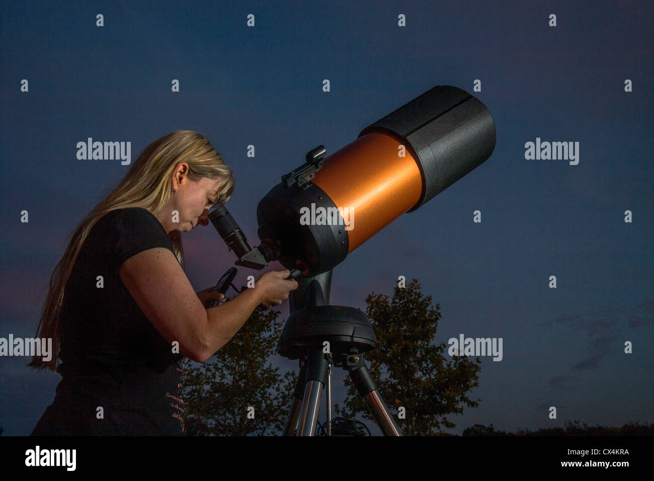 An young woman amateur astronomer uses a 2,000mm catadioptic telescope to look at the stars on an evening in Orange County, CA. Stock Photo