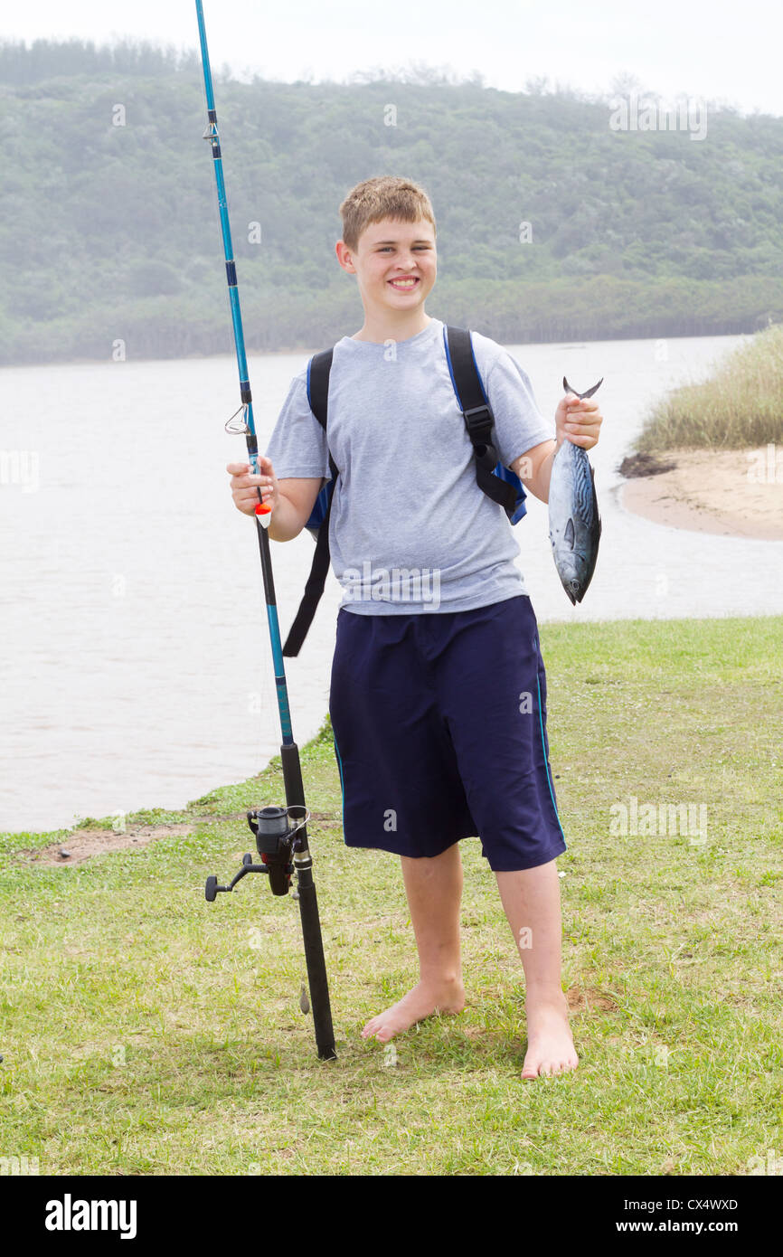 happy teen boy holding fishing rod and a fish he caught Stock