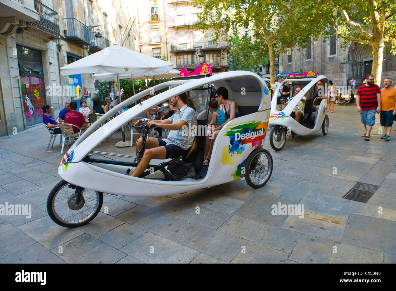 Tourists hire peddle trikes drive through plaza in Barcelona Catalonia Spain ES Stock Photo
