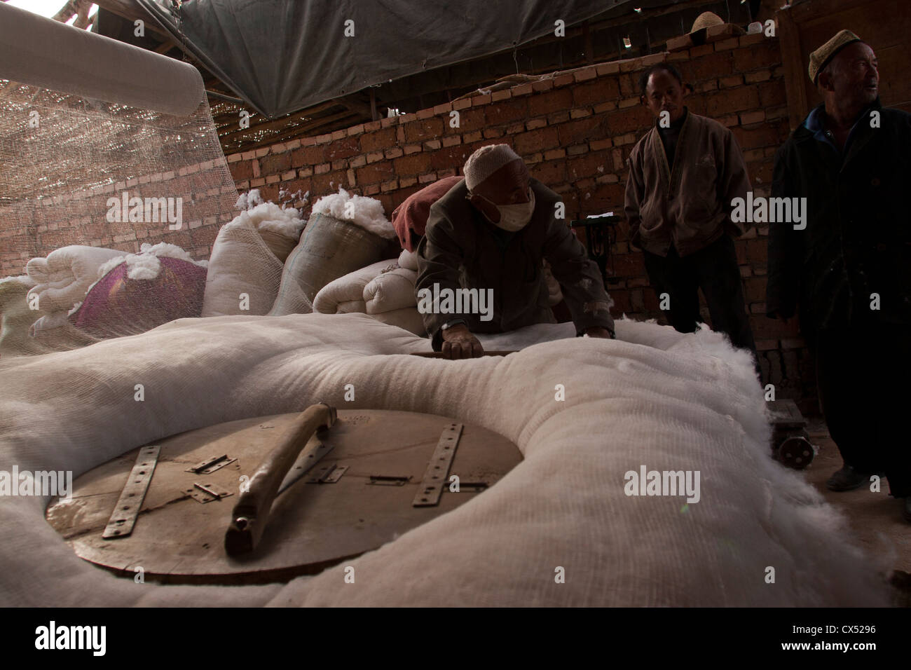 An Uighur man packs cotton before it is spun in Turpan, Xinjiang, China Stock Photo
