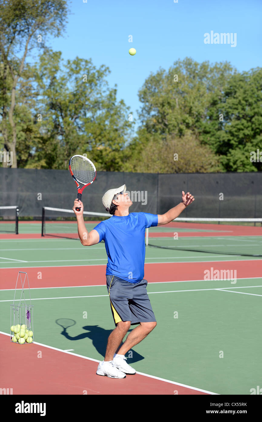 Mature Hispanic tennis player serving ball on court Stock Photo Alamy