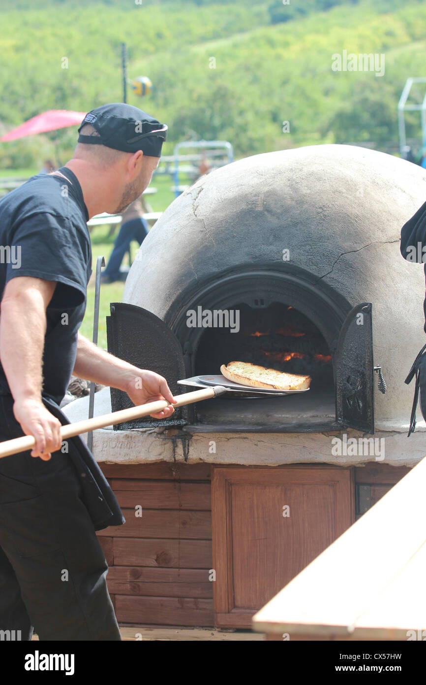 Man outdoor cooking in pizza oven Stock Photo