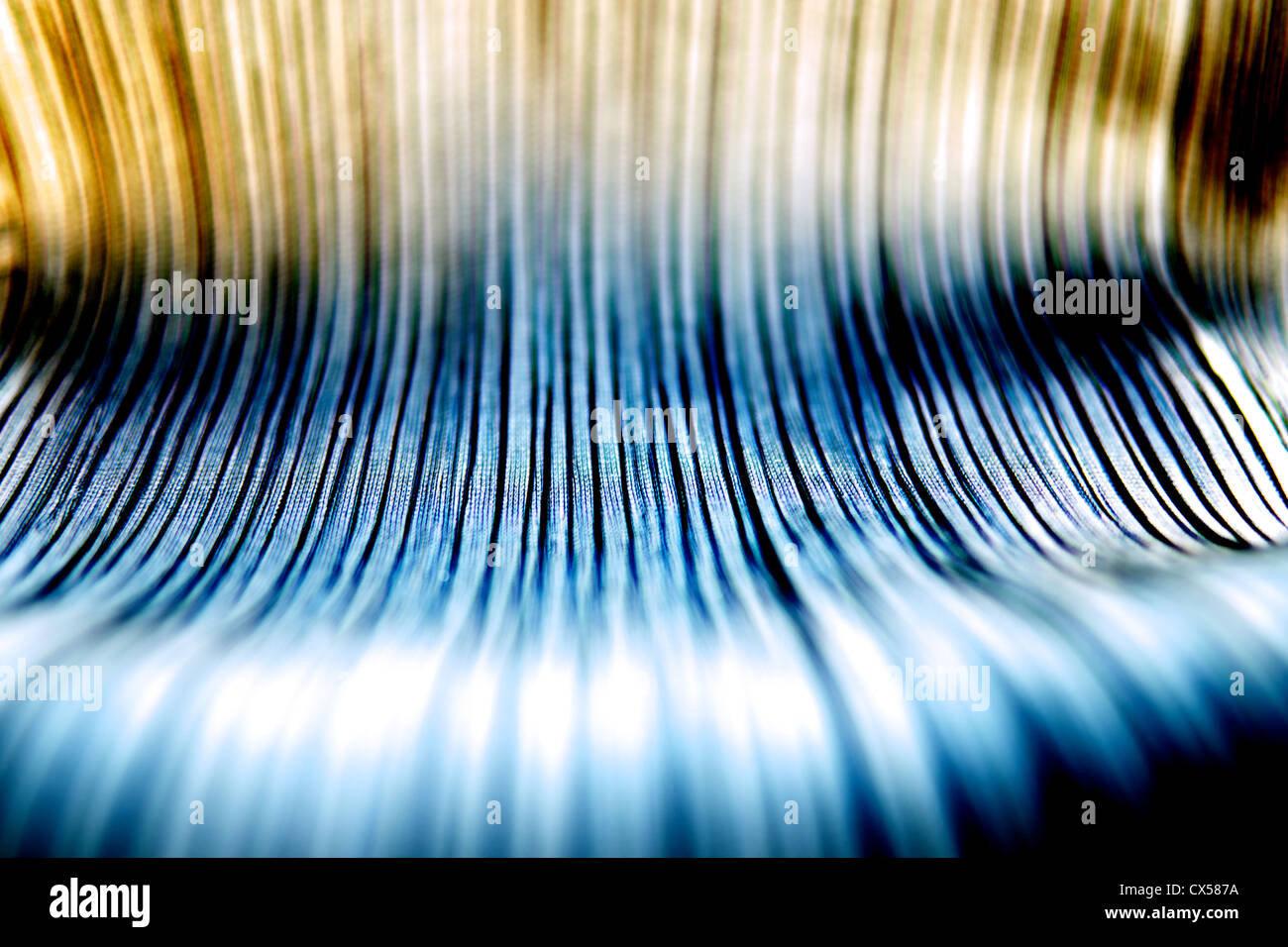 Abstract select focus image of a pleated fabric. Gold and blue hues. Stock Photo