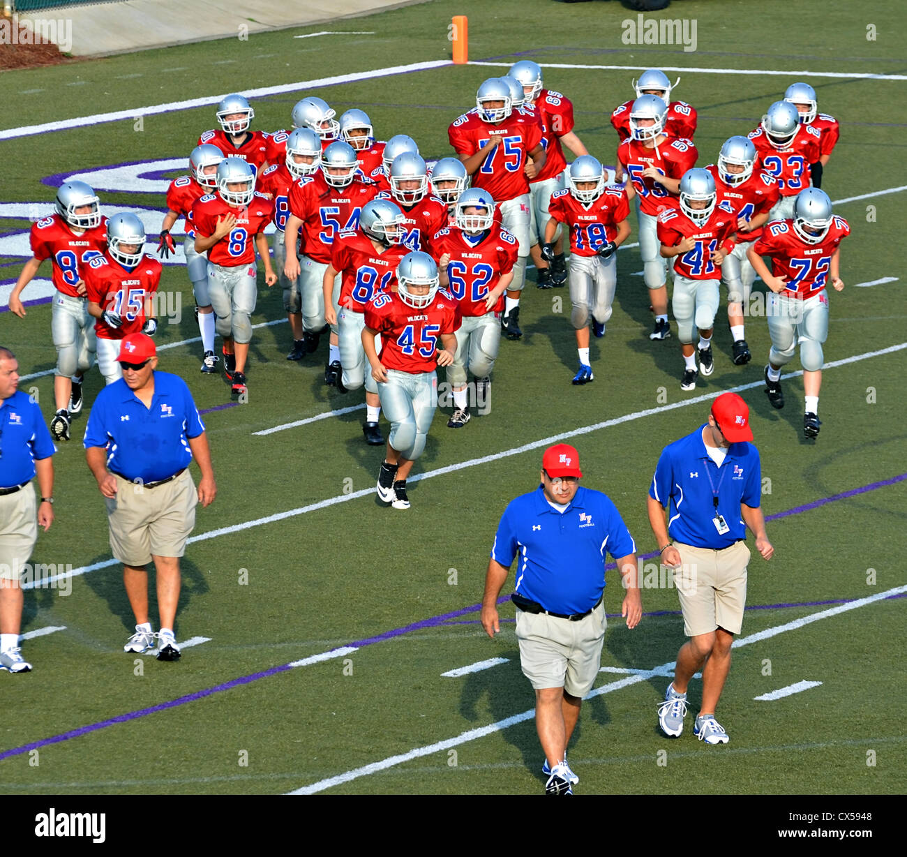 Football coaches leading the team onto the field at the beginning of a game. Stock Photo
