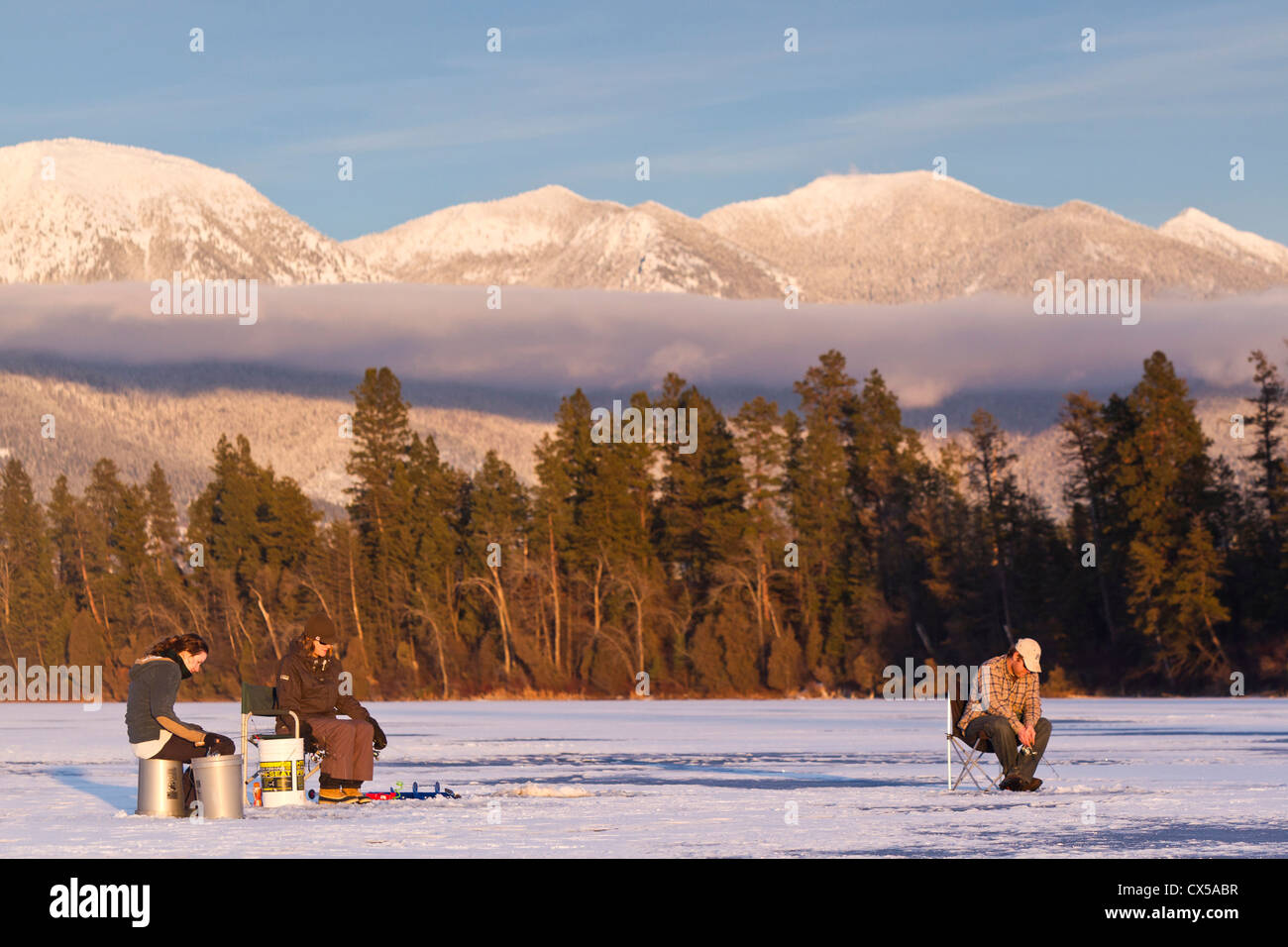 Ice fishing on McWenneger Slough with Swan Mountains in background near