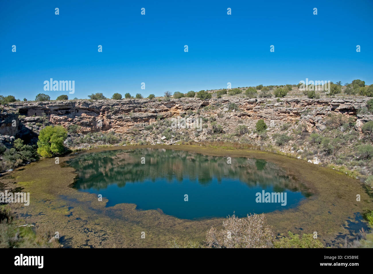 Montezuma's Well with cliff dwellings visible in the far cliffs.  Near Camp Verde Arizona Stock Photo