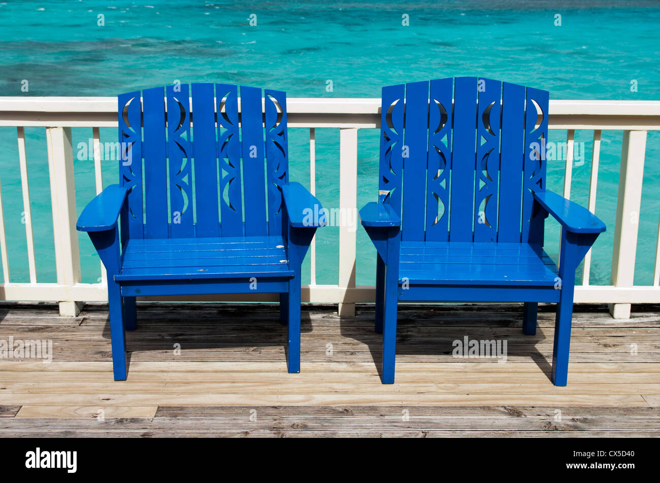 Blue wooden chairs on a deck over turquoise water, Rarotonga, Cook Islands Stock Photo