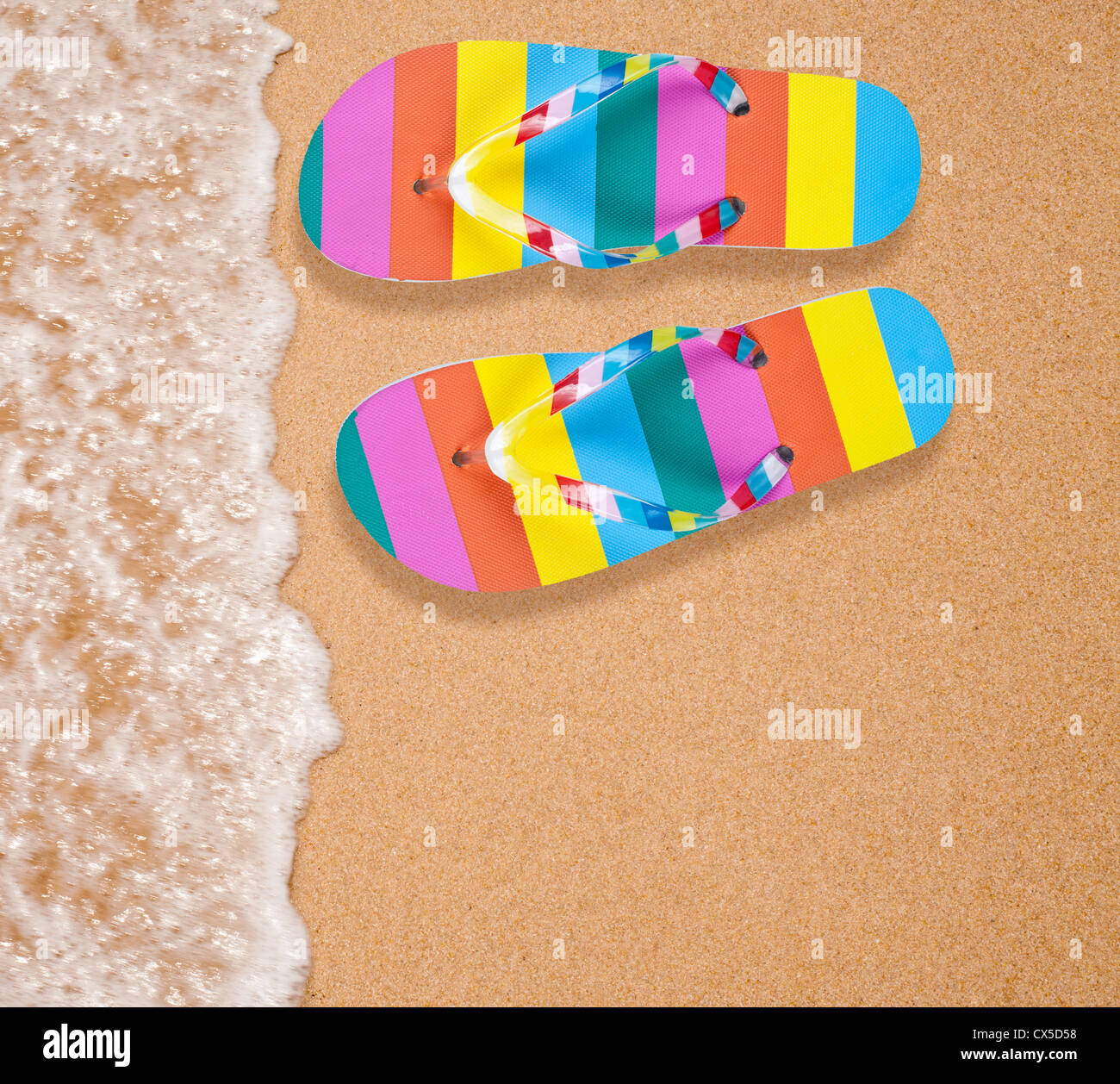Colorful flipflop pair on sea beach Stock Photo