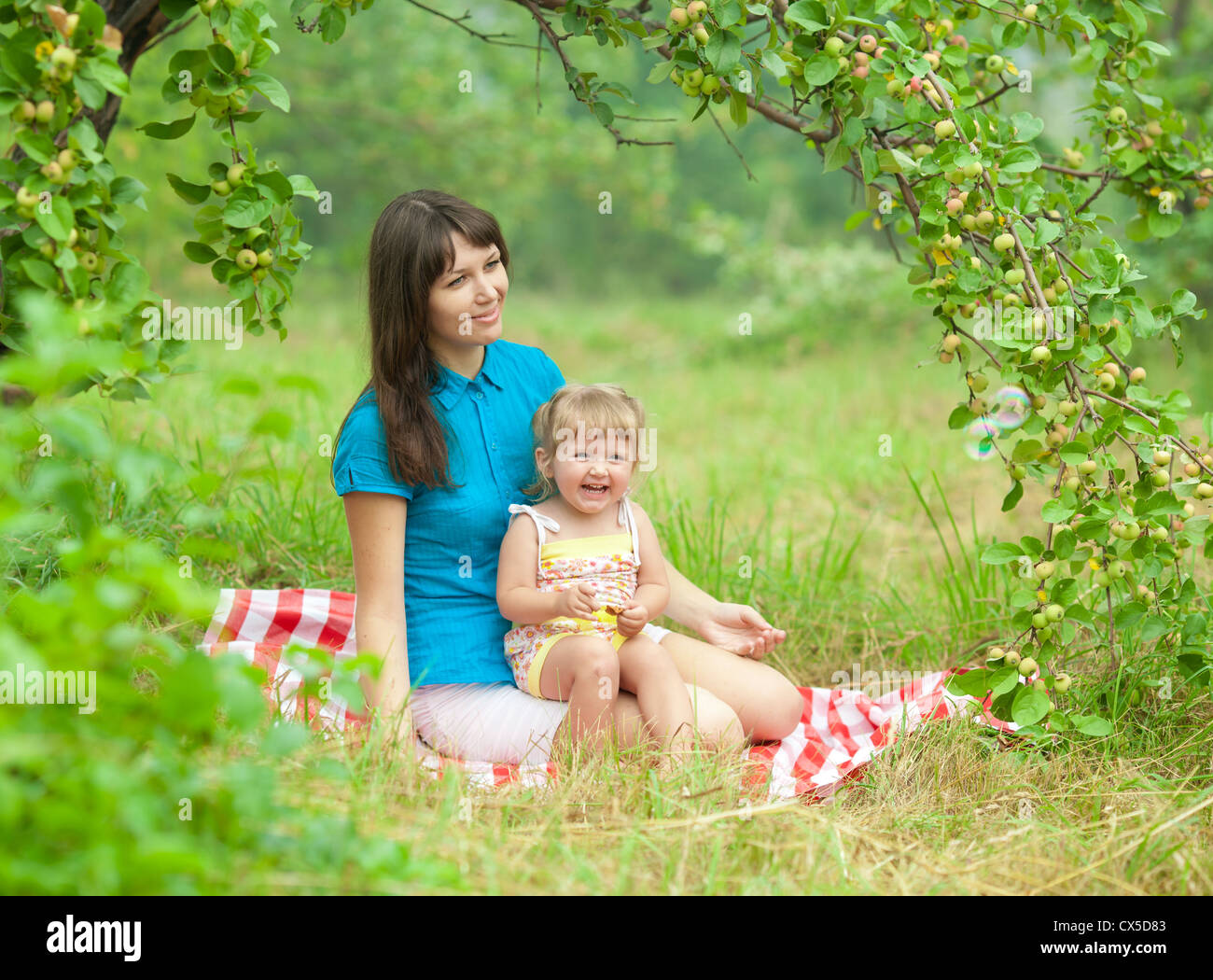 mother and daughter have picnic outdoor under apple tree branch Stock Photo