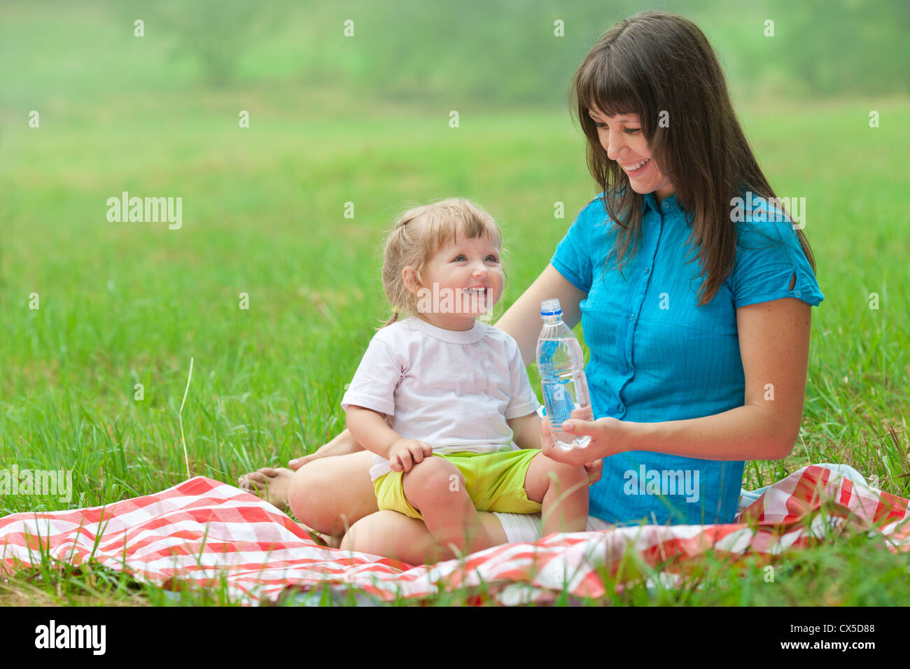 mother and daughter have picnic drinking clear water from bottle Stock Photo