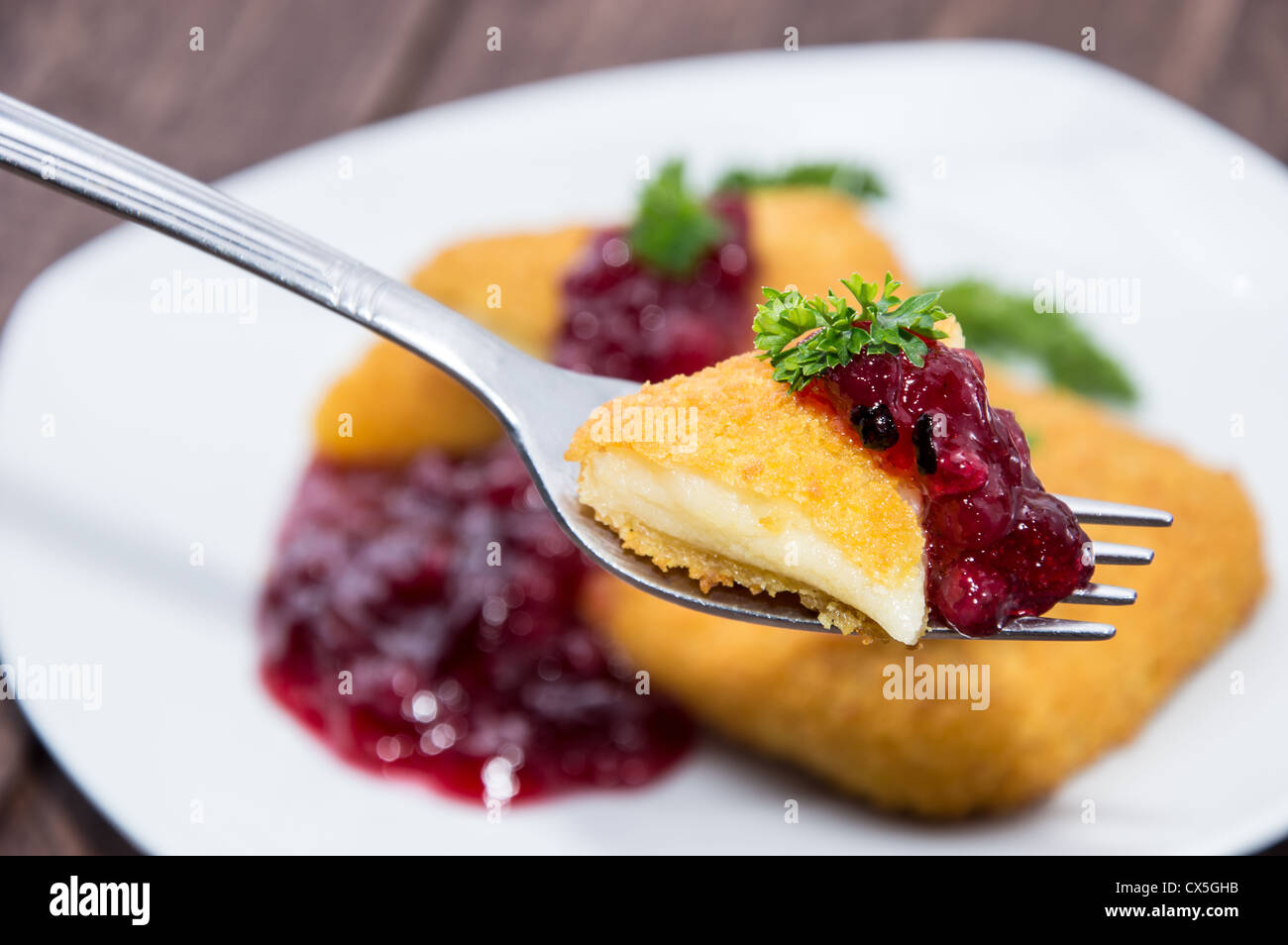 Fried Gouda on a fork on wooden background Stock Photo