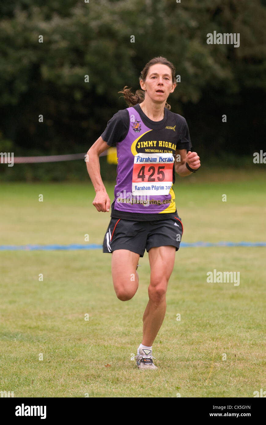 Female half marathon runner nearing finish line in a run for charity, Farnham, Surrey, UK. Stock Photo