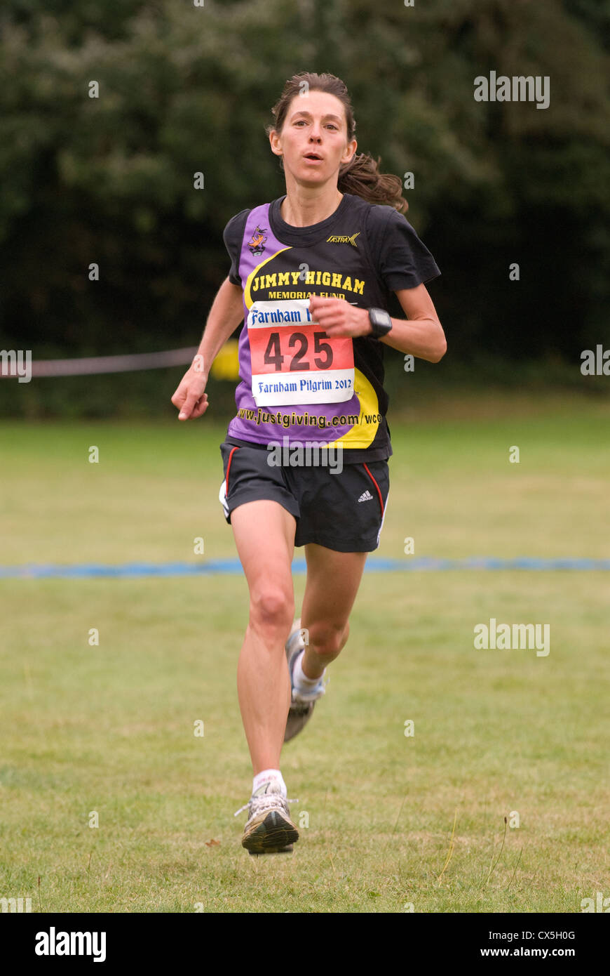 Female half marathon runner nearing finish line in a run for charity, Farnham, Surrey, UK. Stock Photo