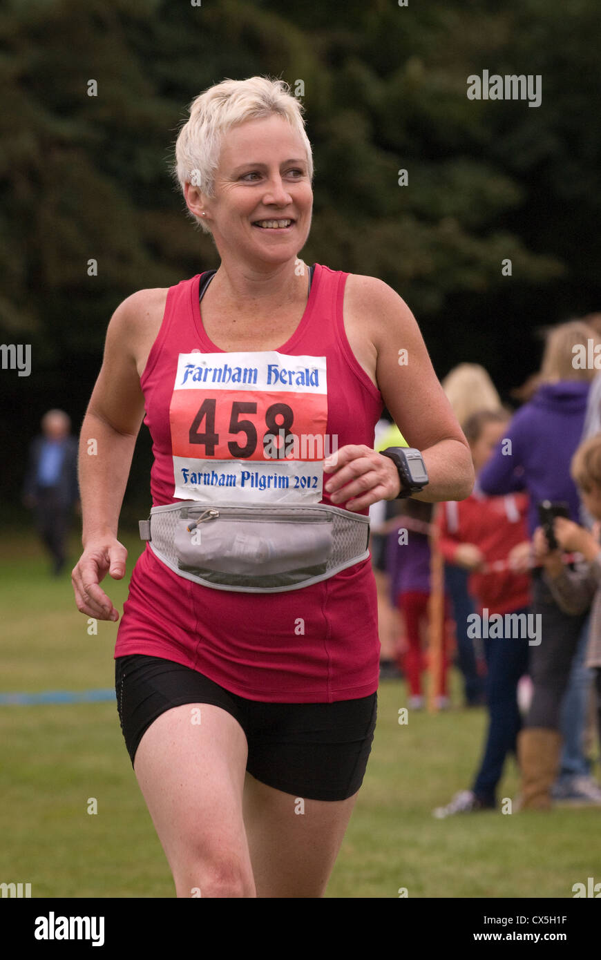 Female half marathon runner nearing finish line in a run for charity, Farnham, Surrey, UK. Stock Photo