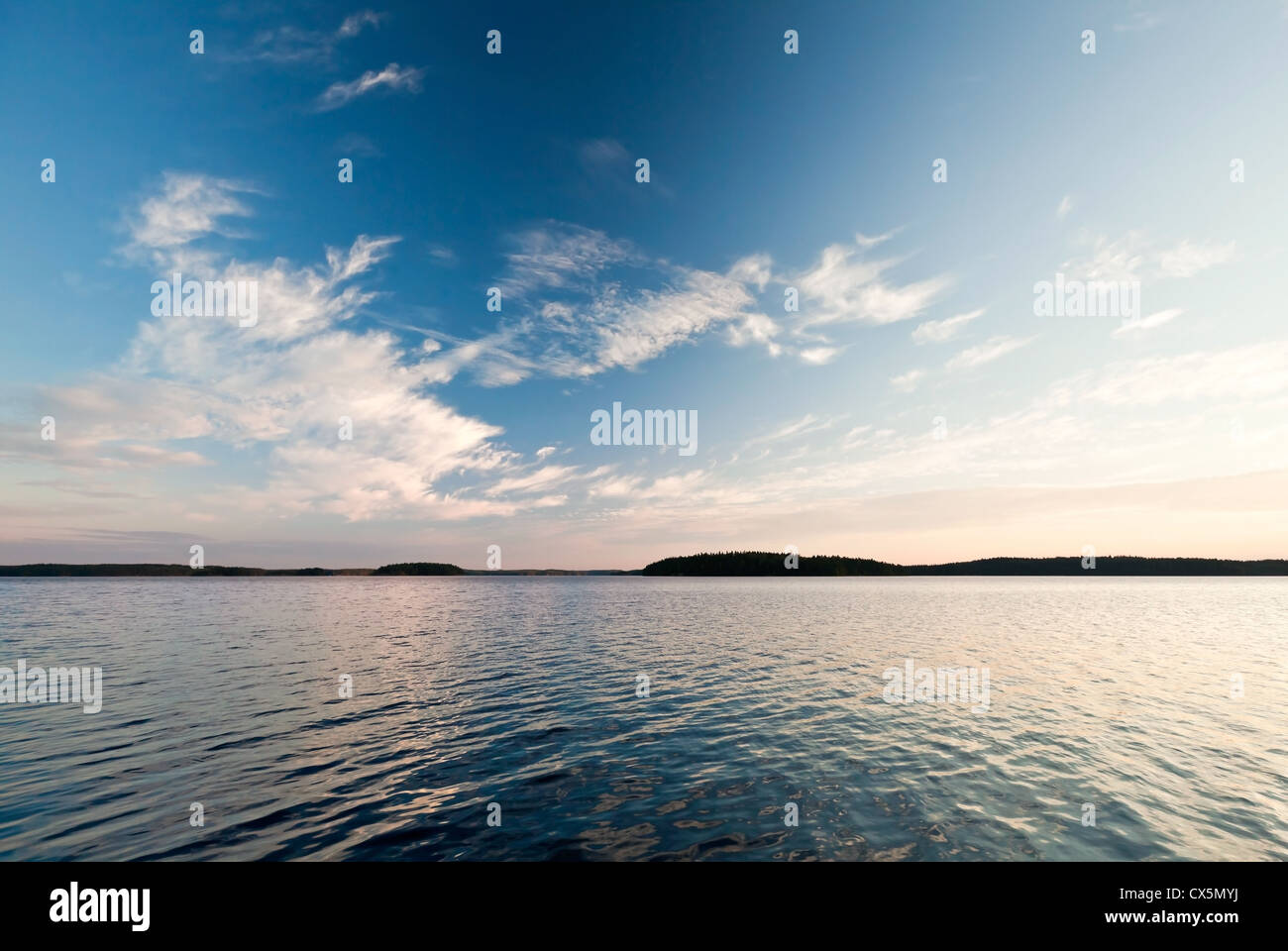Coastline of Saimaa lake with clouds reflected on still water Stock Photo
