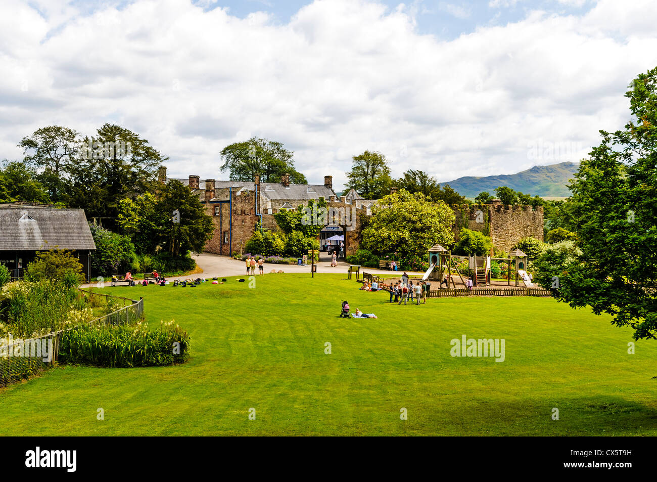A green pleasant lawn with a modern children's play area for relaxation and picnics opposite the old stables, Muncaster Castle Stock Photo