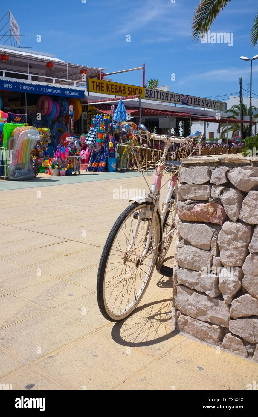an old bike left on beach in front of shops and bars in majorca Stock Photo