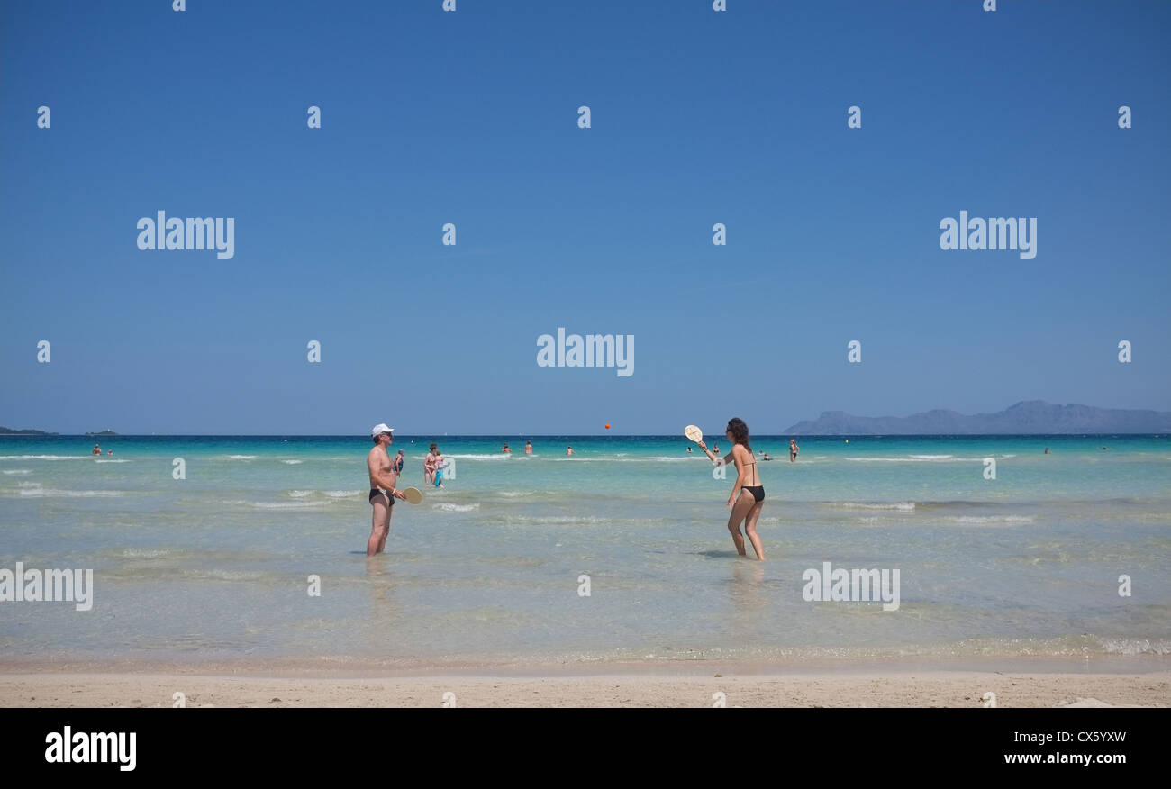 beach goers play tennis on golden sands of  Alcudia beach in Mallorca Stock Photo
