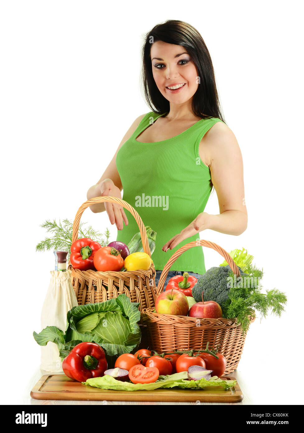 Young smiling woman standing at the table with variety of fresh raw ...