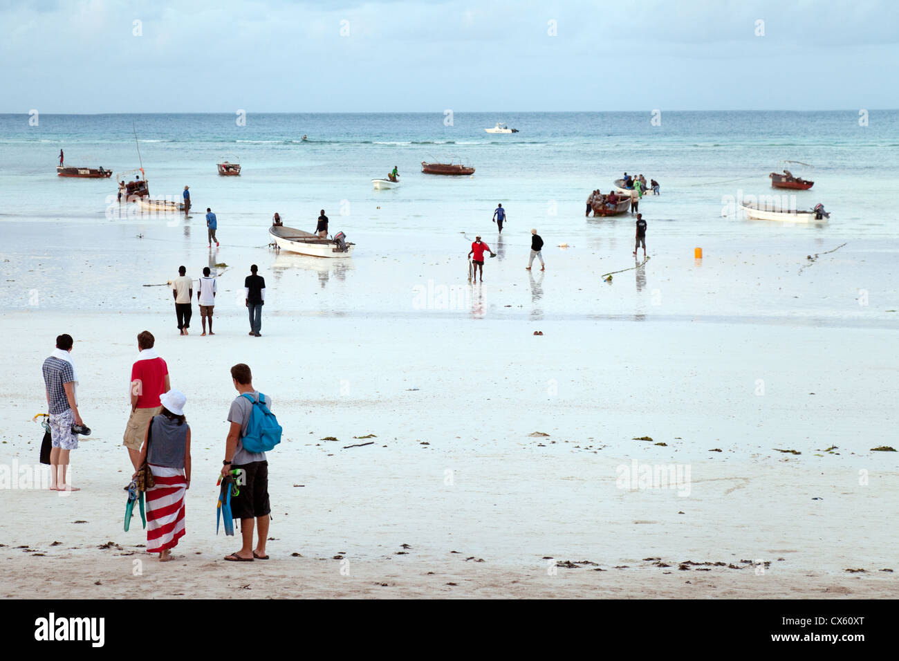Tourists and locals on the beach at Kizimkazi at dawn to go dolphin watching and swimming with dolphins, Zanzibar Africa Stock Photo