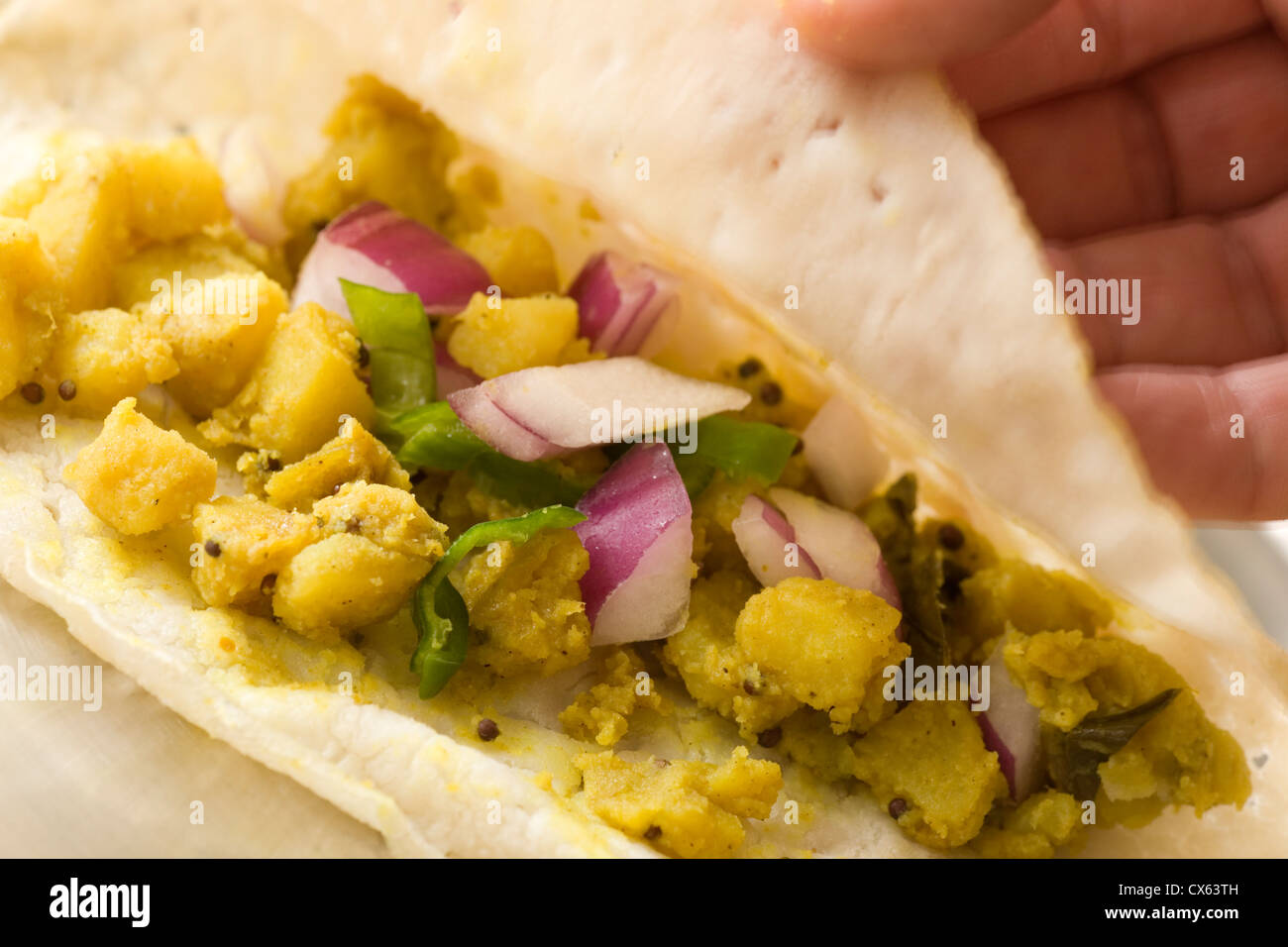 The inside of a home made masala dosa showing the spicy potato filling