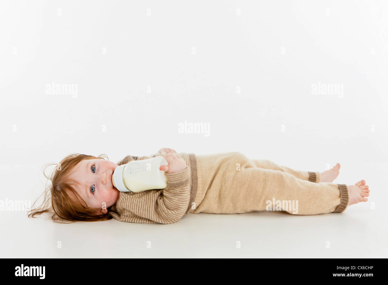 A baby girl lying down with a bottle of milk Stock Photo