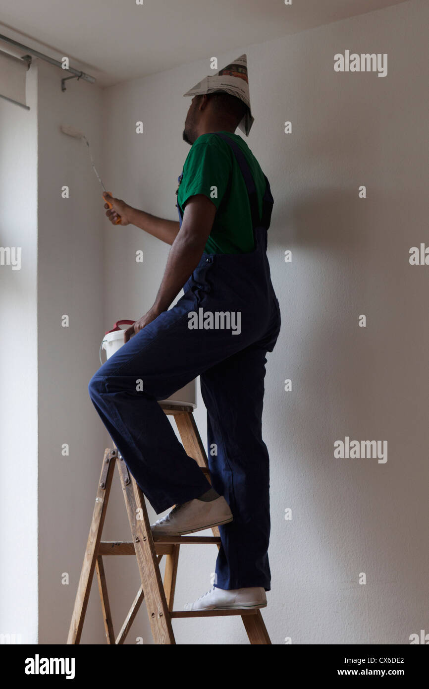 A man standing on a ladder and painting a wall Stock Photo - Alamy